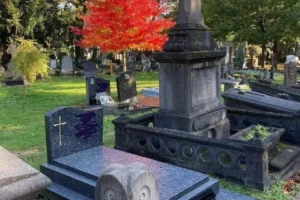 Sépulture en granit et érable rouge dans un cimetière en automne.