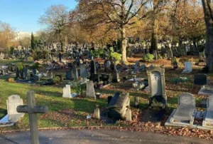 Sépultures anciennes et feuillage d'automne dans un cimetière paysagé.