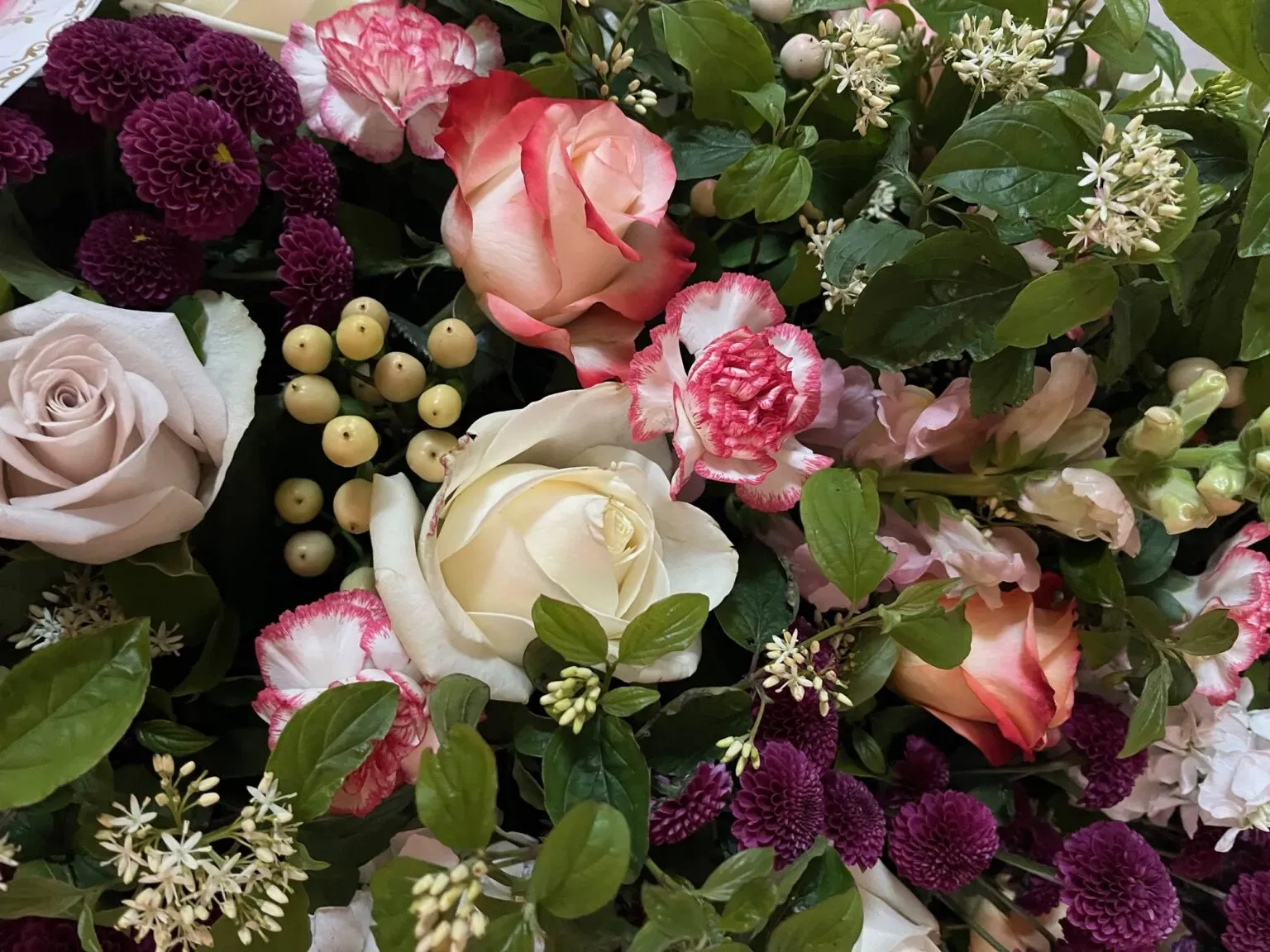Composition florale variée avec des roses blanches et roses.